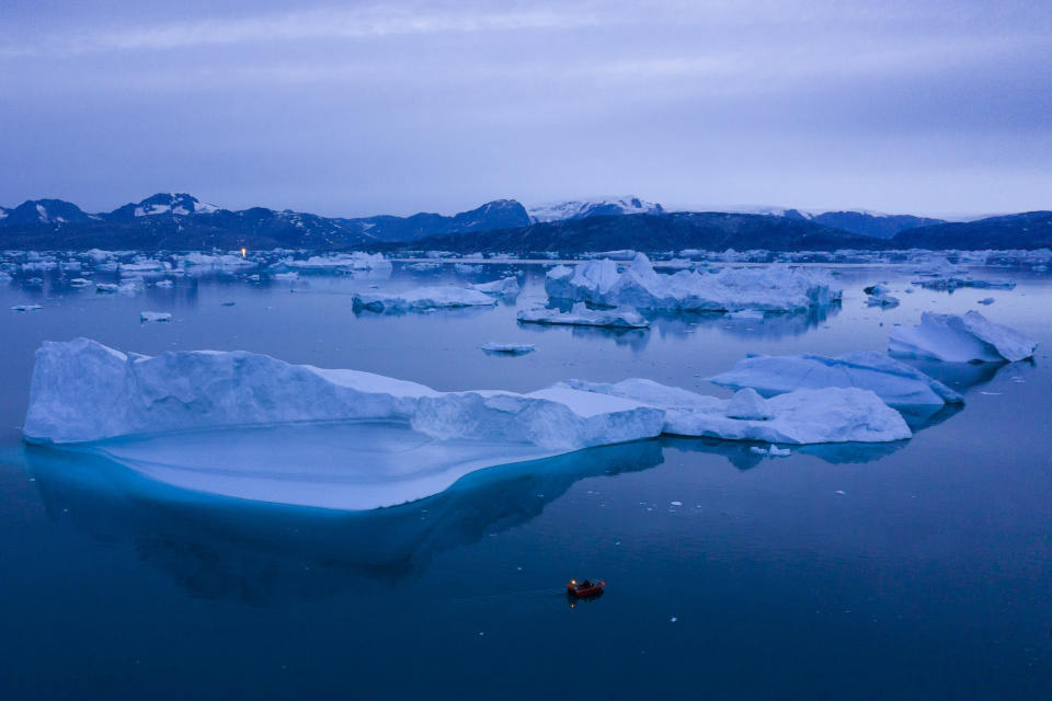 In this Aug. 15, 2019, photo, a boat navigates at night next to large icebergs near the town of Kulusuk, in eastern Greenland. Greenland's ice has been melting for more than 20 years, but in 2019, it's as if Earth's refrigerator door has been left open, and it means a potentially large rise in the world's sea levels. (AP Photo/Felipe Dana)