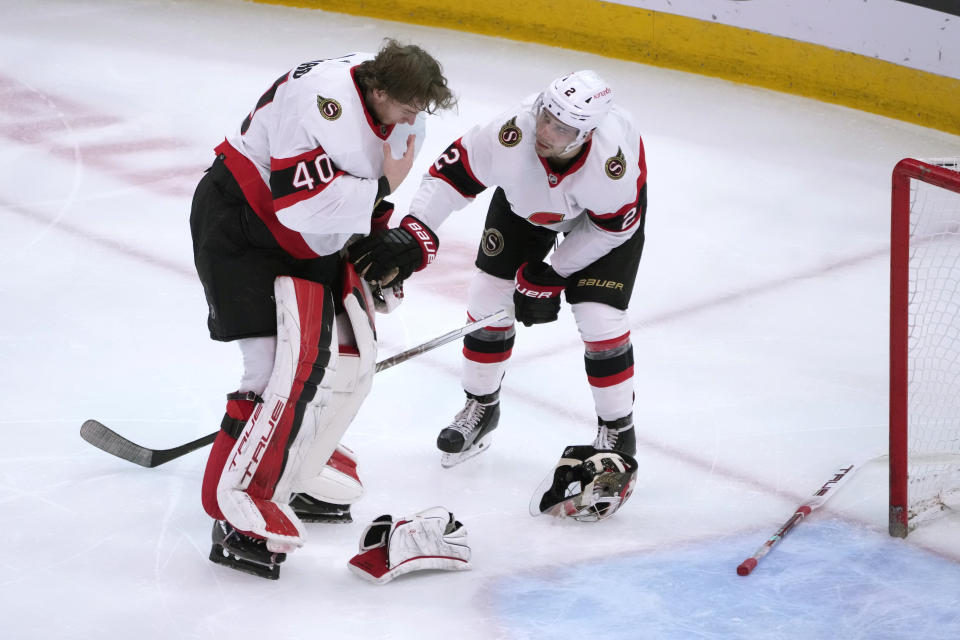 Ottawa Senators goaltender Mads Sogaard (40) is checked on by Artem Zub after Sogaard was scored on by Chicago Blackhawks' Seth Jones during the second period of an NHL hockey game, Monday, March 6, 2023, in Chicago. (AP Photo/Charles Rex Arbogast)