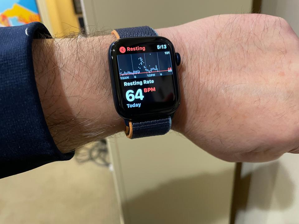 An Apple Watch shows a resting heart rate reading.