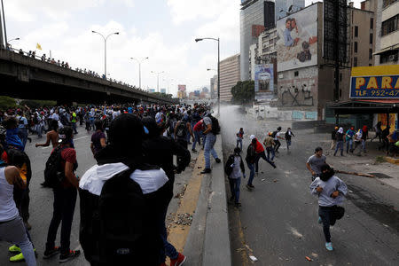 Demonstrators run from a police water cannon during an opposition rally in Caracas, Venezuela April 6, 2017. REUTERS/Carlos Garcia Rawlins