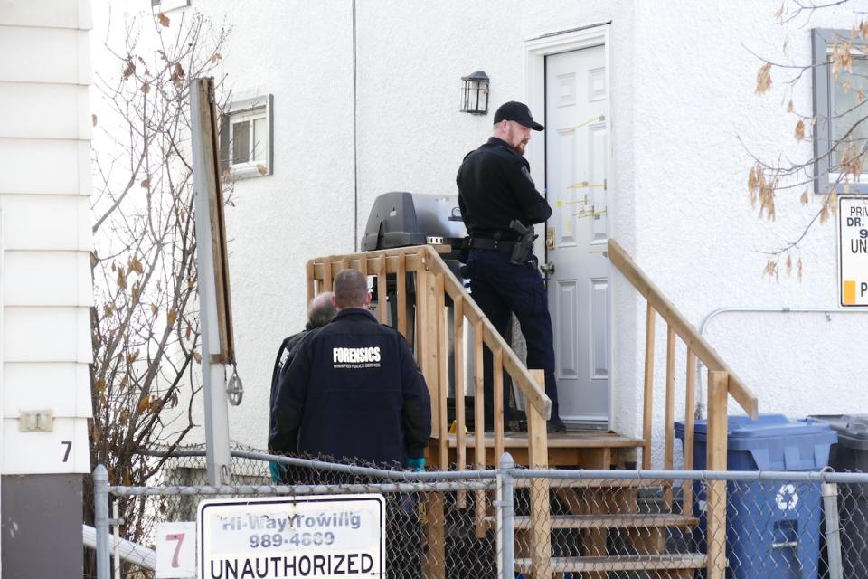 Investigators were seen placing evidence markers around the yard of a house in Winnipeg's West Alexander area on Monday, including tags indicating multiple bullet holes in a back door. (Jeff Stapleton/CBC - image credit)