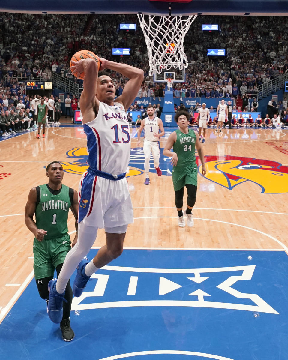 Kansas guard Kevin McCullar Jr. (15) gets past Manhattan guard Shaquil Bender (1) to dunk the ball during the first half of an NCAA college basketball game Friday, Nov. 10, 2023, in Lawrence, Kan. (AP Photo/Charlie Riedel)