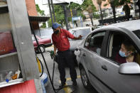 A worker wearing a face mask amid the new coronavirus pandemic works to fill up a client's gas tank at a PDVSA state oil company gas station in Caracas, Venezuela, Monday, May 25, 2020. The first of five tankers loaded with gasoline sent from Iran this week is expected to temporarily ease Venezuela's fuel crunch while defying Trump administration sanctions targeting the two U.S. foes. (AP Photo/Matias Delacroix)