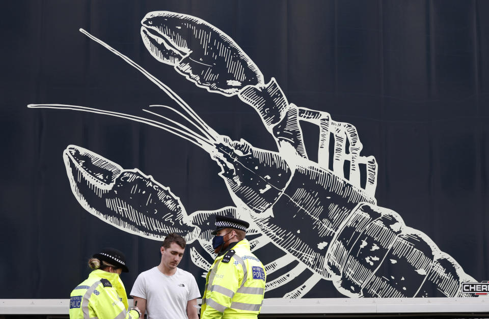 Police speak to a shellfish export truck driver as he is stopped for an unnecessary journey in London, Monday, Jan. 18, 2021, during a demonstration by British Shellfish exporters to protest Brexit-related red tape they claim is suffocating their business. The drivers were later stopped by police and issued with fines for an 'unnecessary journey' due to the national lockdown to curb the spread of the coronavirus. (AP Photo/Alastair Grant)