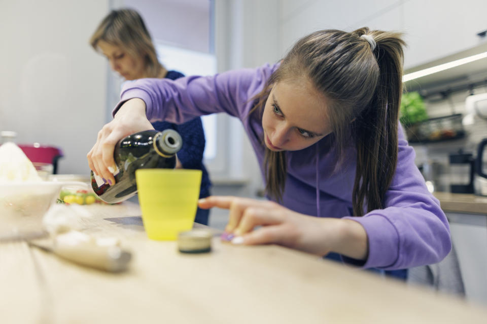 Someone pouring vanilla extract into a cup.