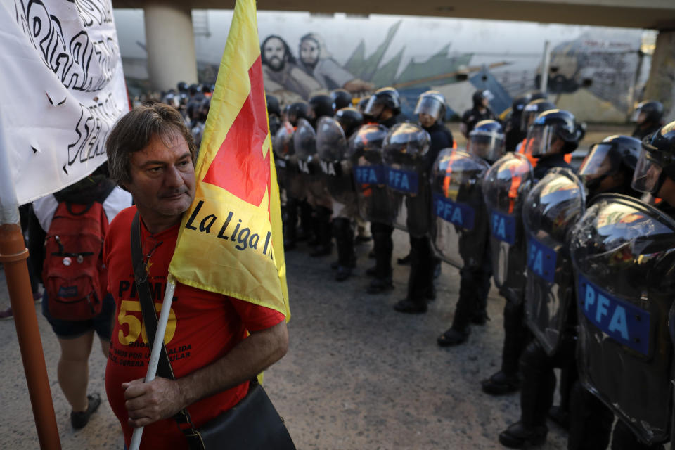 Un manifestante sostiene una bandera frente a una línea de policías durante una huelga general en las afueras de Buenos Aires, Argentina, el jueves 6 de abril de 2017. (AP Foto/Natacha Pisarenko)