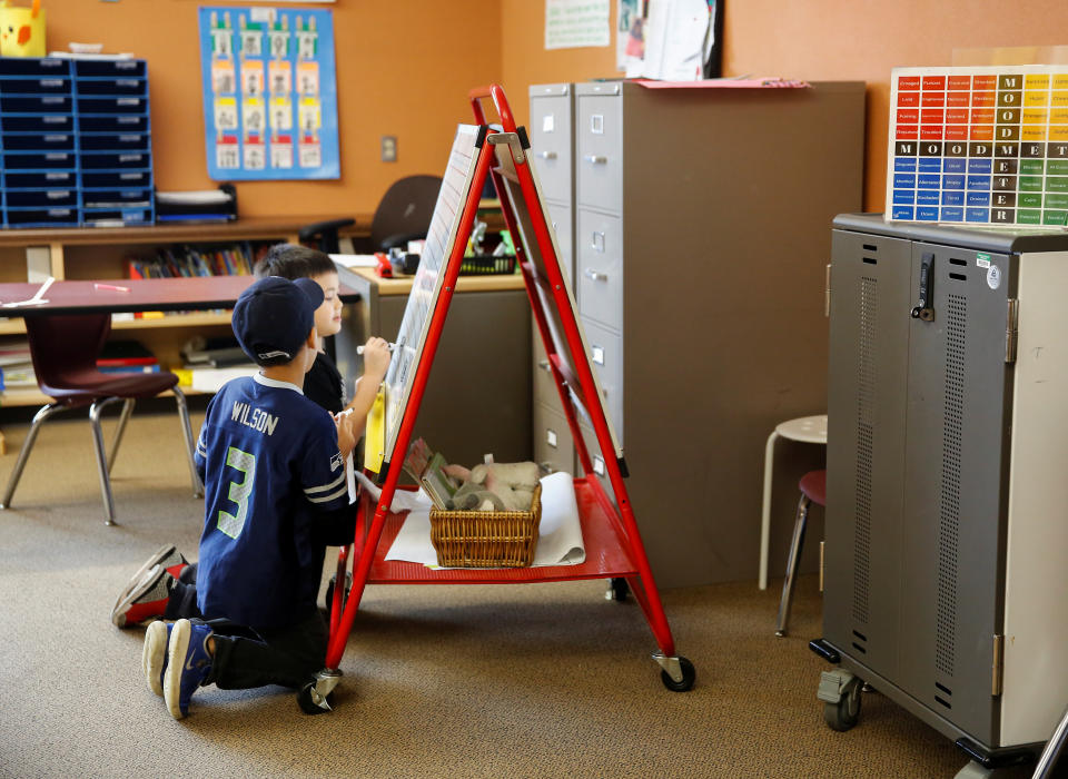 Liam Zuercher and Neil Branham draw on a whiteboard during a daycare for children of healthcare workers and first responders at Midway Elementary School during the coronavirus disease (COVID-19) outbreak in Des Moines, Washington, U.S. March 26, 2020. REUTERS/Lindsey Wasson