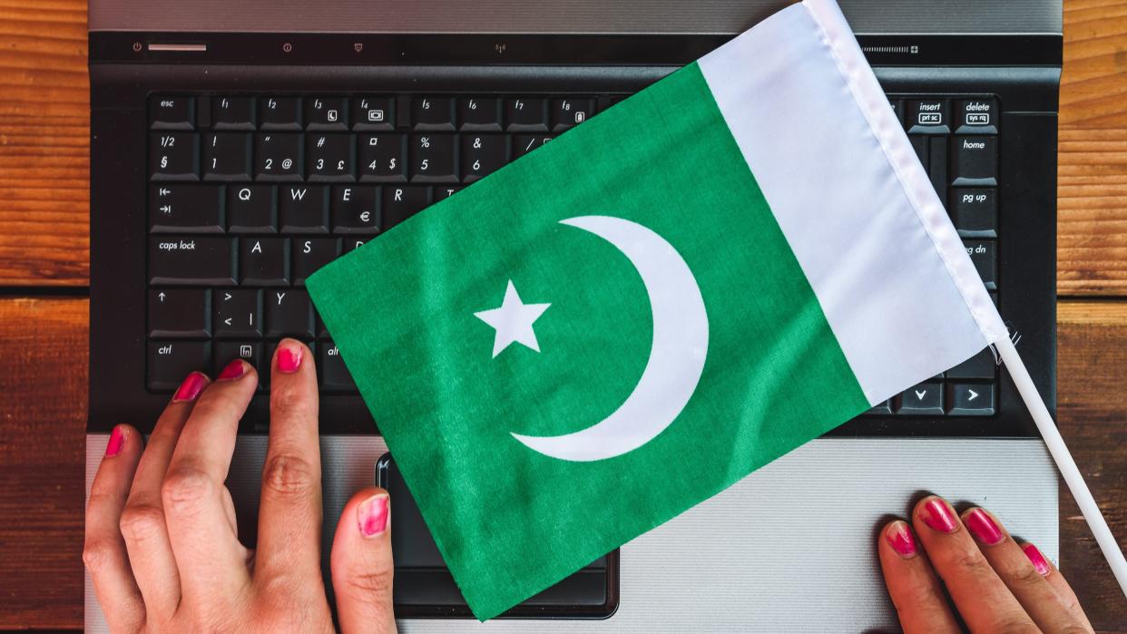  Woman hands and flag of Pakistan on laptop keyboard. 