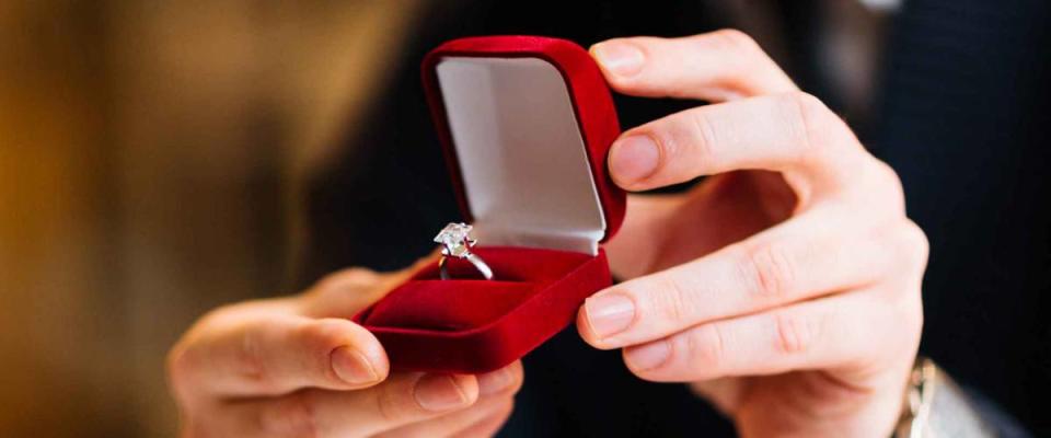 Male hands with red velvet box containing engagement ring with brilliant