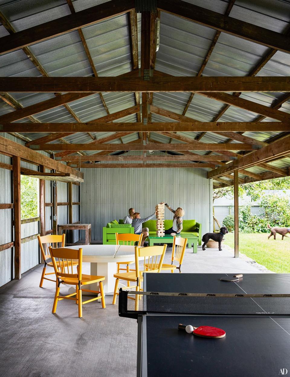 The family enjoys game time inside the corrugated-metal pool cabana designed by Roy McMakin.