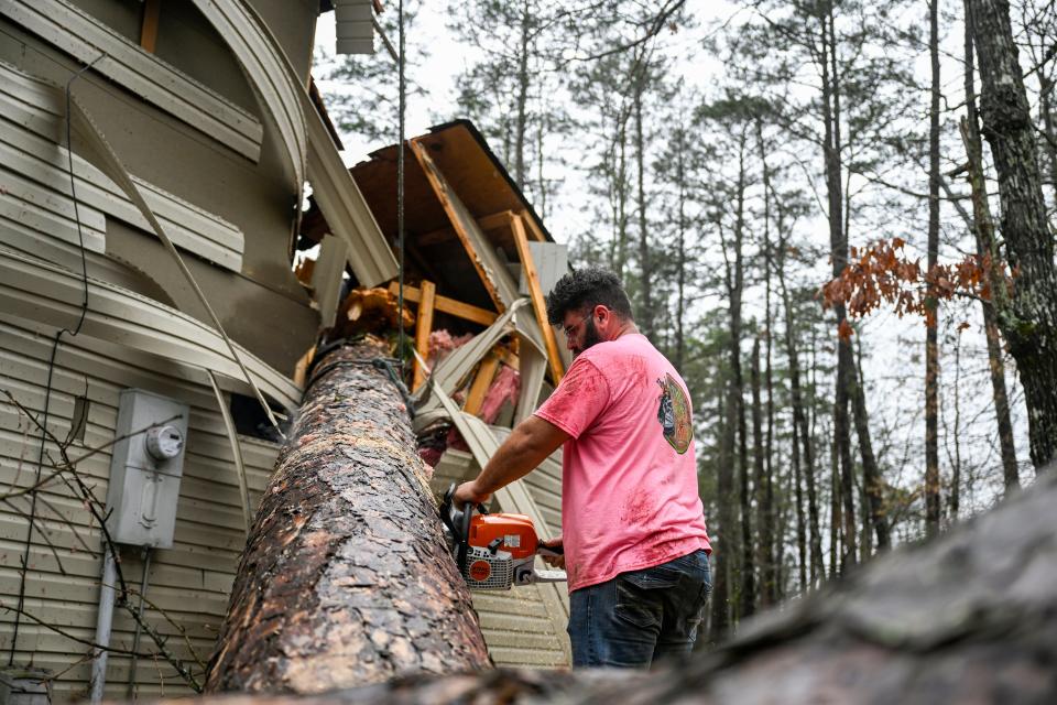 Jojo Gargano uses a chainsaw to cut up a tree that fell on a house in Hot Springs Village, Ark., Friday, March 15, 2024, after a tornado came through the area overnight.