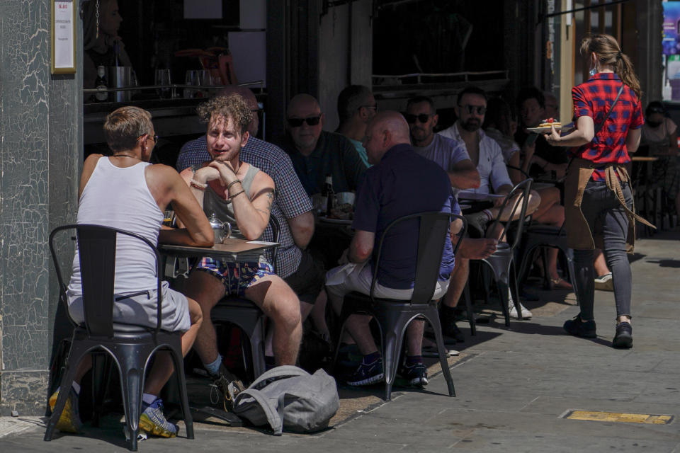 People sit at outdoor tables at a restaurant in Soho, in London, Monday, June 14, 2021. British Prime Minister Boris Johnson is expected to confirm Monday that the next planned relaxation of coronavirus restrictions in England will be delayed as a result of the spread of the delta variant first identified in India. (AP Photo/Alberto Pezzali)