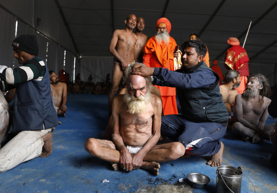 In this Jan. 27, 2019, photo, Hindu men get their hair cut in a ritual before becoming Naga Sadhus or naked holy men at Sangam, the confluence of three holy rivers during the Kumbh Mela or pitcher festival in Prayagraj Uttar Pradesh state, India. At every Kumbh, including this year's, thousands of devotees were initiated into the reclusive sect of the Naga Sadhus, naked, ash-smeared cannabis-smoking Hindu warriors and onetime-armed defenders of the faith who for centuries have lived as ascetics in jungles and caves. (AP Photo/ Rajesh Kumar Singh)