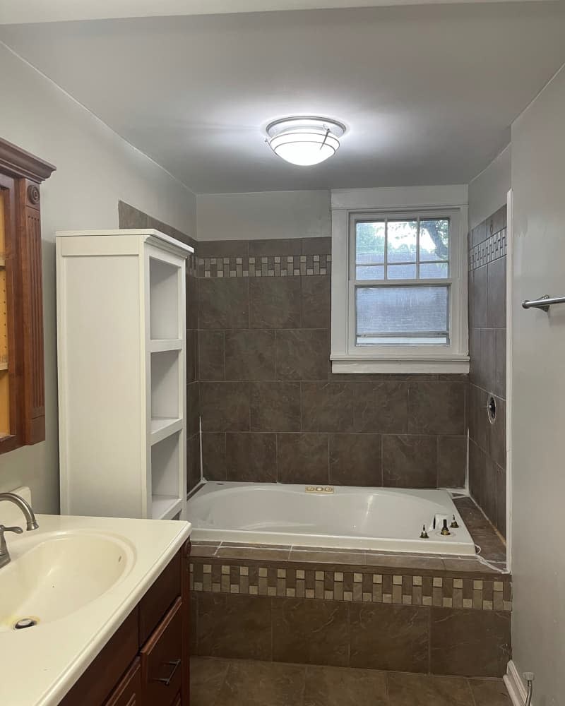 Brown tiles in bathroom tub before renovation.