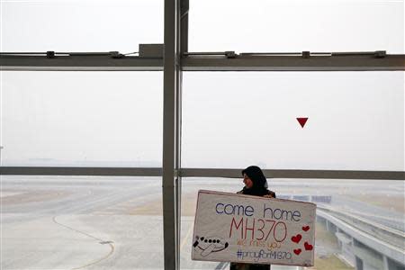 A woman holds a sign of support and hope for the passengers of the missing Malaysia Airlines flight MH370 she made and brought to the Kuala Lumpur International Airport March 11, 2014. REUTERS/Damir Sagolj