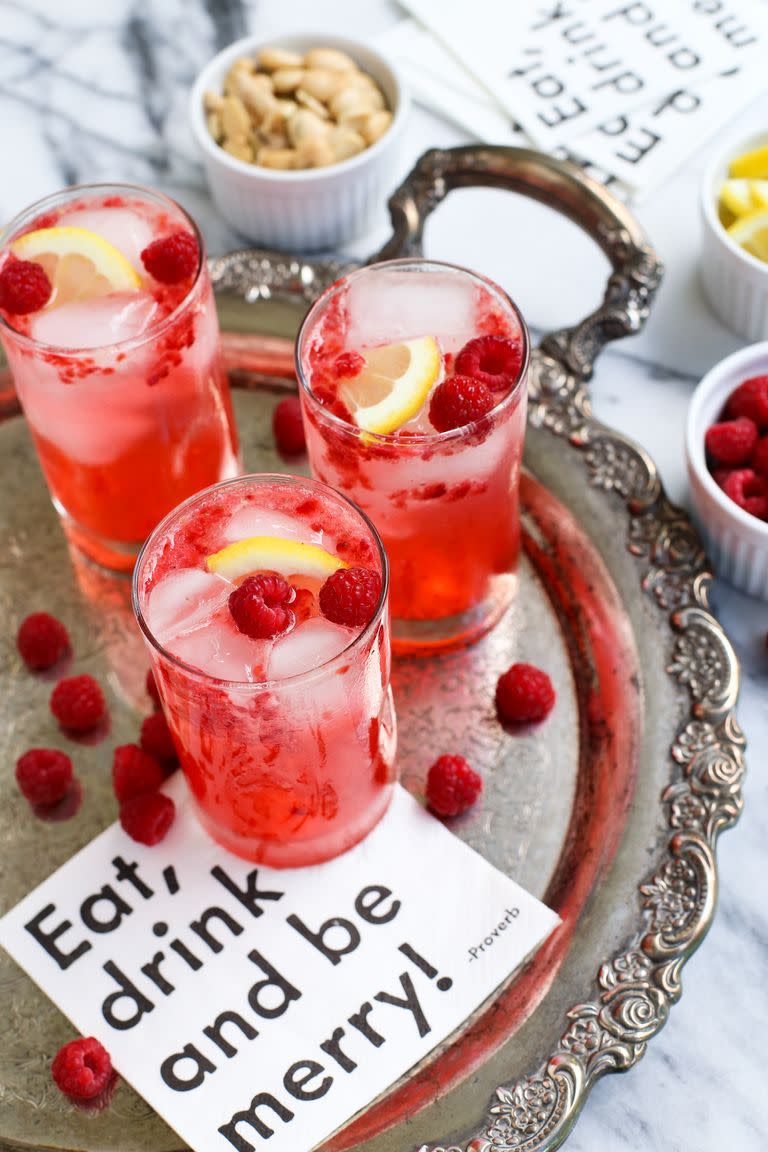 raspberry smash cocktails in 3 glasses on tray with raspberries
