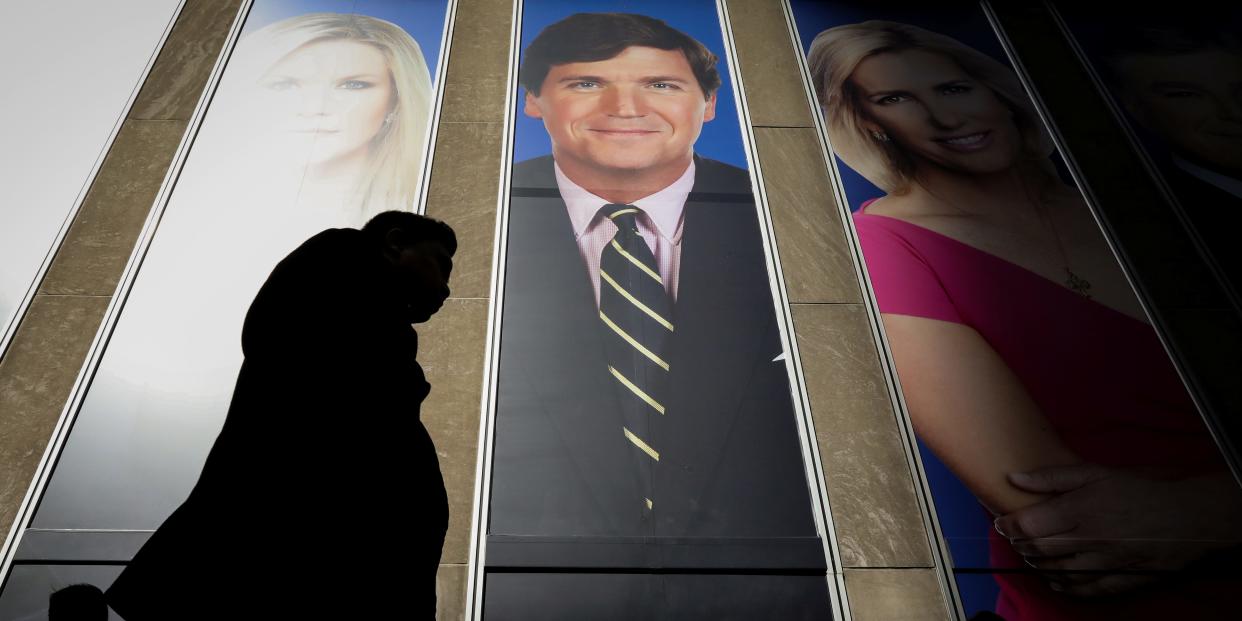 People pass by a promo of Fox News host Tucker Carlson on the News Corporation building in New York, US, March 13, 2019.