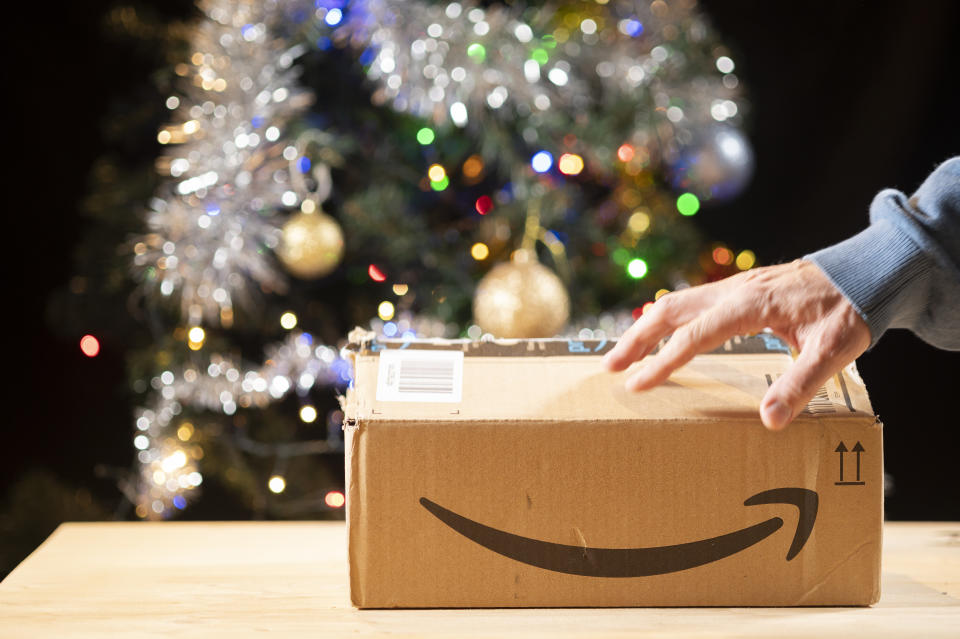 A person opens a package at home from a well-known online sales company.In the background you can see a Christmas tree ready for the holidays