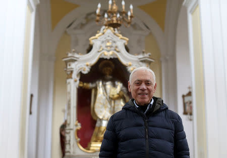 The church's priest Giuseppe Gambardella, 76, known to everyone as Don Peppino, poses in front of the St. Felice statue, patron in Pomigliano D'Arco, near Naples, Italy, February 21, 2018. Picture taken February 21, 2018. REUTERS/Alessandro Bianchi