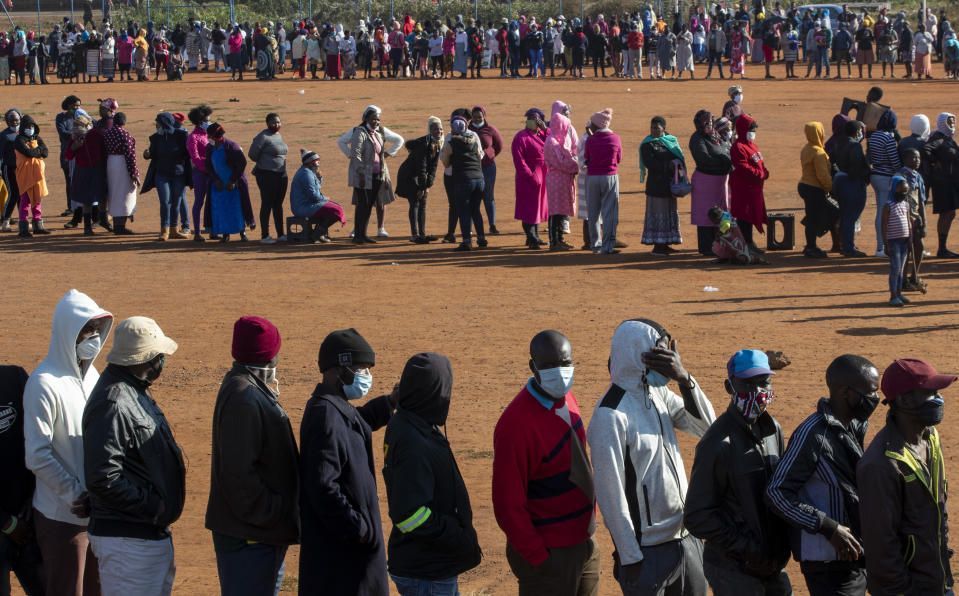 FILE — In this May 20, 2020 file photo, people affected by the coronavirus economic downturn line up to receive food parcels in Pretoria, South Africa. South Africa's COVID-19 response has been marred by corruption allegations around its historic dollars 26 billion economic relief package, as the country with the world's fifth highest number of COVID-19 cases braces for more. (AP Photo/Themba Hadebe/File)