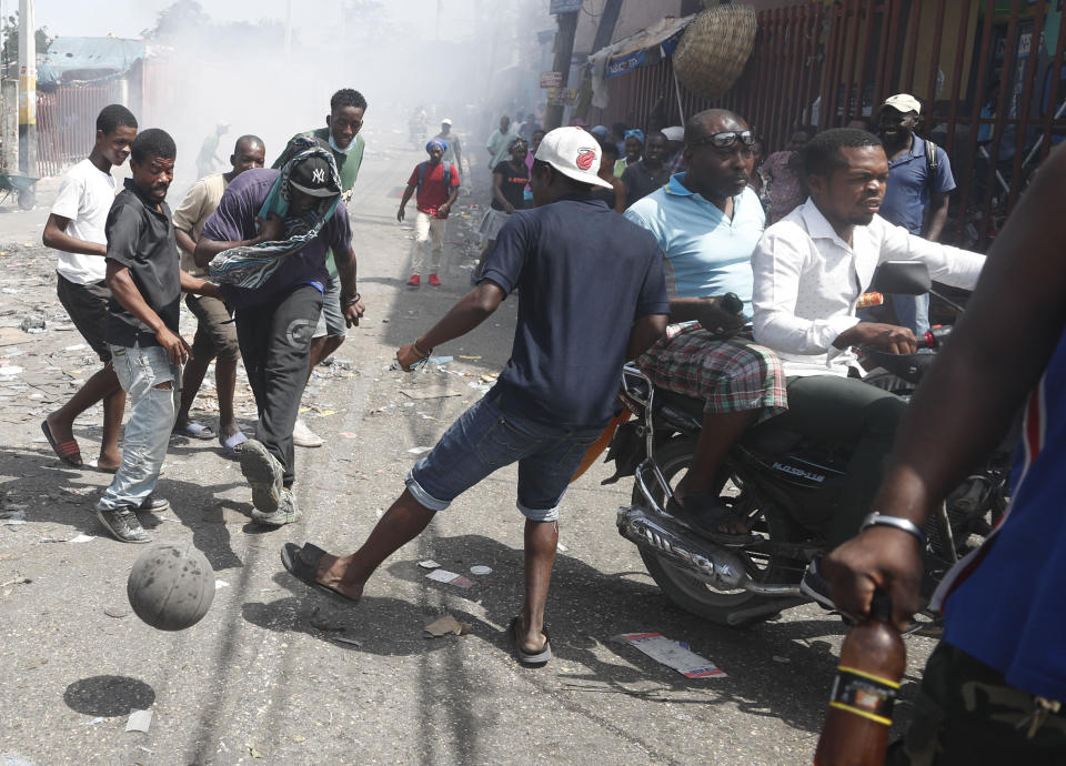 Demonstrators play soccer with a basketball during an anti-government protest on a street in Port-au-Prince, Haiti, Friday, Oct. 11, 2019. Protesters burned tires and spilled oil on streets in parts of Haiti's capital as they renewed their call for the resignation of President Jovenel Moïse just hours after a journalist was shot to death. (AP Photo/Rebecca Blackwell)