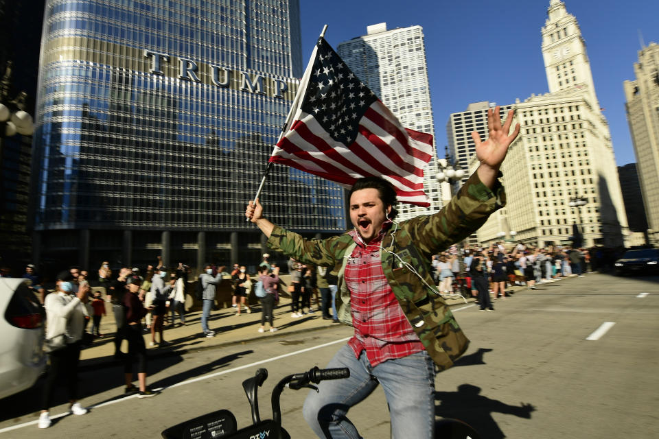 A supporter of President-elect Joe Biden celebrates while riding his bike outside Trump Tower Saturday, Nov. 7, 2020, in Chicago. Democrat Joe Biden defeated President Donald Trump to become the 46th president of the United States on Saturday, positioning himself to lead a nation gripped by the historic pandemic and a confluence of economic and social turmoil. (AP Photo/Paul Beaty)