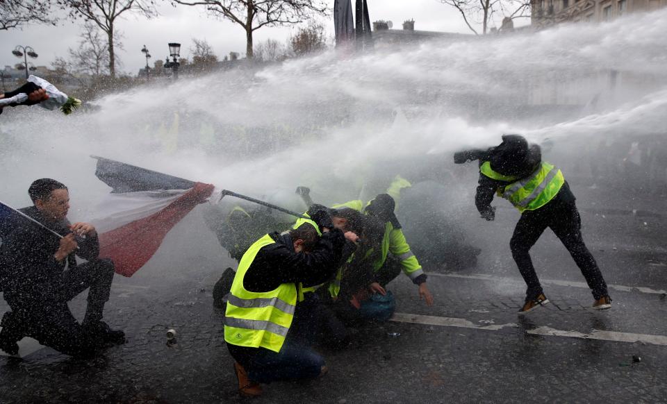 Protesters wearing yellow vests are sprayed with water cannons as they clash with riot police near the Arc de Triomphe during a demonstration over high fuel prices in Paris, Dec. 1, 2018. (Photo: Yoan Valat/EPA-EFE/REX/Shutterstock)