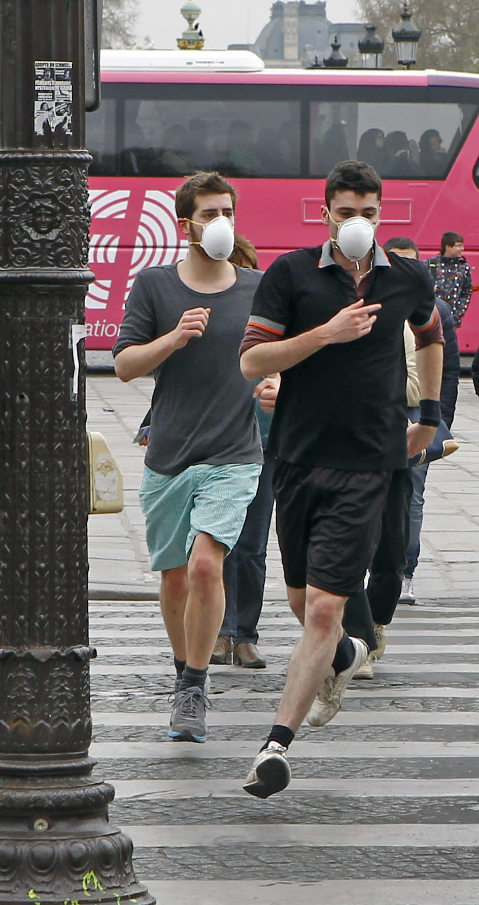 Two joggers wearing protective masks run on the Concorde square in Paris, Monday, March 17, 2014. Paris is taking drastic measures to combat its worst air pollution in years, banning around half of the city's cars and trucks from its streets in an attempt to reduce the toxic smog that's shrouded the City of Light for more than a week.(AP Photo/Remy de la Mauviniere)