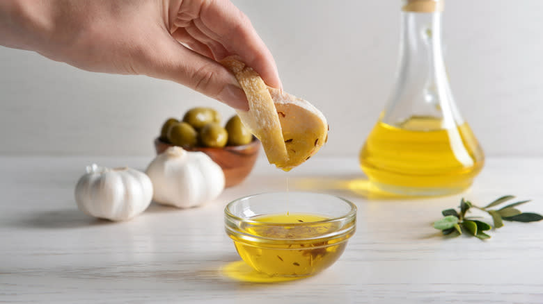 Dipping bread in olive oil with garlic and olives