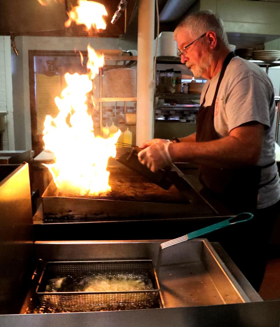 Rollin Kellogg, partial owner of City Cafe in downtown Murfreesboro prepares a burger on the grill as flames rise on Wednesday, Aug. 31, 2022. City Cafe is closed on Mondays including during Labor Day.