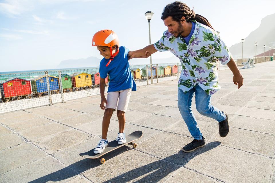 father helping his son to skateboard