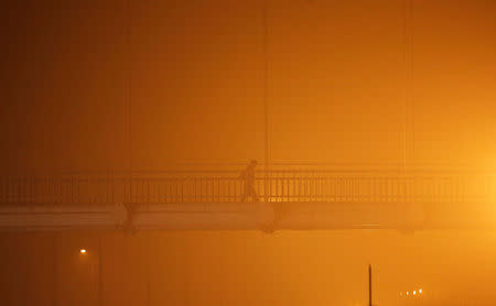 A man walks on a pedestrian bridge amidst the heavy smog in New Delhi, November 6, 2016. REUTERS/Adnan Abidi