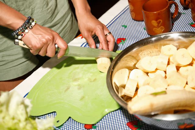 <p>Lebo Lukewarm/Courtesy of Intrepid Travel</p> Chopping bananas during a homestay cooking class.