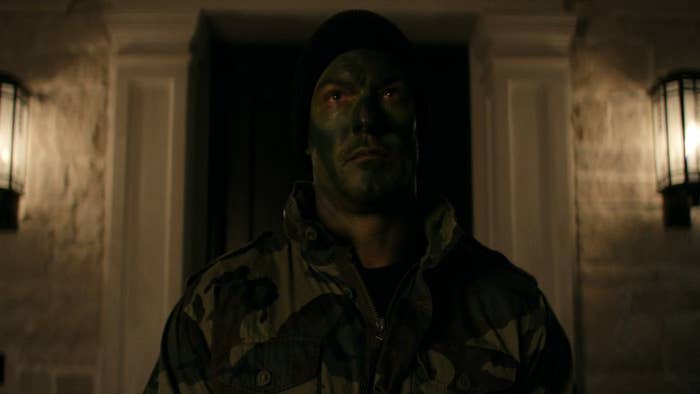 Jack Reacher with his face painted with war paint and wearing military camouflage dress