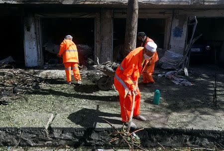 Afghan municipality workers clean up a road at the site of a suicide attack in Kabul, Afghanistan July 24, 2017. REUTERS/Omar Sobhani