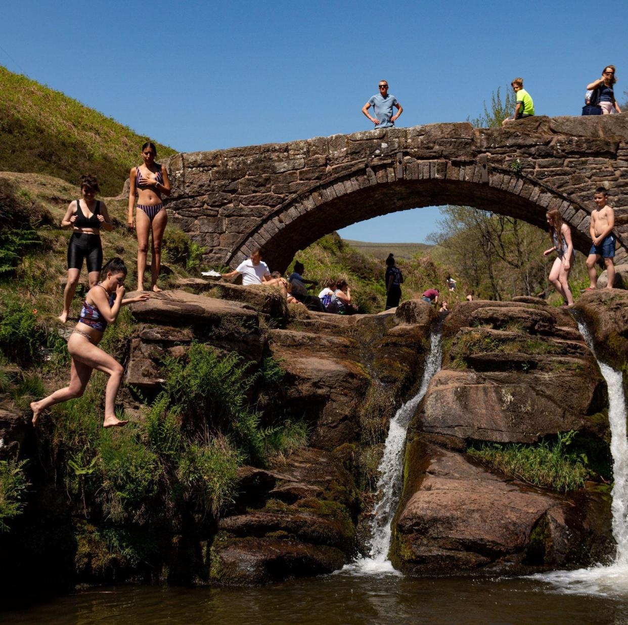 People enjoying the good weather by Three Shires Head on the river Dane