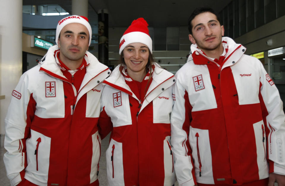 Georgian skiers from left: Iason Abramishvili, Nino Tsiklauri and IAlexi Banianidze pose for photos before their departure to Sochi, at Tbilisi Airport in Georgia, Thursday, Feb. 6, 2014. The Georgian Olympic team left for Sochi on Thursday following a decision not to boycott the Sochi Winter Olympics, a subject that stirred a lot of controversy in Georgian society. (AP Photo/ Shakh Aivazov)