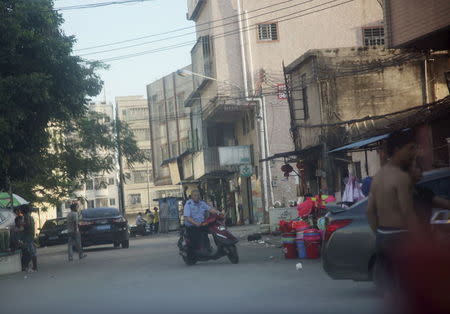 A Chinese â€œchengguanâ€, or urban management official, whose responsibilities include working with police to help enforce minor city rules and regulations, drives a moped in an area known for housing illegal foreign workers in Dongguan in Southern China May 14, 2015. REUTERS/James Pomfret