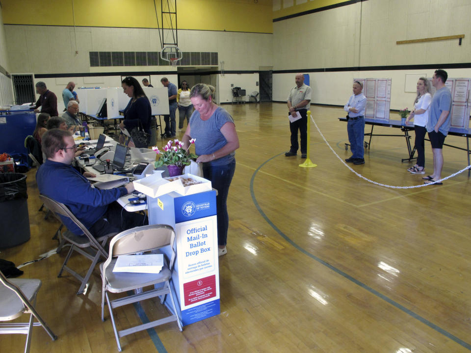 Washoe County voters line up inside a gymnasium at Reed High School in Sparks, Nev. on Tuesday, June 14, 2022, to cast their primary election ballots either by making selections on voting machine computer screens or dropping the ballot that was mailed to them into a ballot drop box if they haven't already returned it in the mail. The spotlight in Nevada was on the GOP primary where Republicans will pick nominees to try to unseat Democratic incumbents in the U.S. Senate and governor's mansion in November. (AP Photo/Scott Sonner).