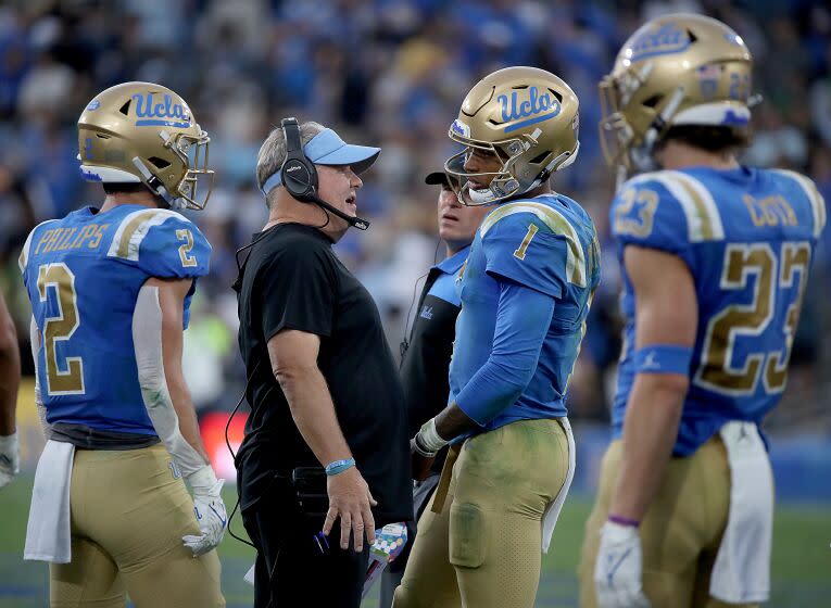 PASADENA, CALIF. - OCT. 23, 2021. UCLA head coach Chip Kelly talks with quarterback Dorian Thompson-Robinson.