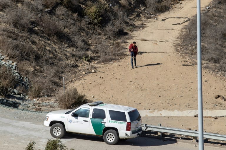 A man with a child in his arms walks toward a US patrol after illegally crossing the US-Mexico border