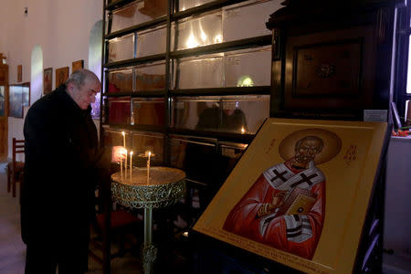 A man lights candles at Saint Nikolla church near where fallen Greek World War Two soldiers are buried, in Kelcyra, Albania January 24, 2018. Picture taken January 24, 2018. REUTERS/Florion Goga