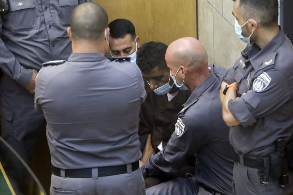 Zakaria Zubeidi, one of the six Palestinians who escaped from a high-security prison earlier this week is surrounded by guards as they stand in a courtroom in Nazareth, Israel, after he and three other Palestinian fugitives were captured on Saturday, Sept. 11, 2021. Israeli police on Saturday said they have arrested four of the six Palestinians who broke out of a maximum-security prison this week including Zubeidi a famed militant leader whose exploits over the years have made him a well-known figure in Israel. (AP Photo/Sebastian Scheiner)