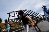 <p>Opposition supporters carry materials to build a barricade to block an avenue while rallying against President Nicolas Maduro in Caracas, Venezuela, May 15, 2017. (Carlos Garcia Rawlins/Reuters) </p>