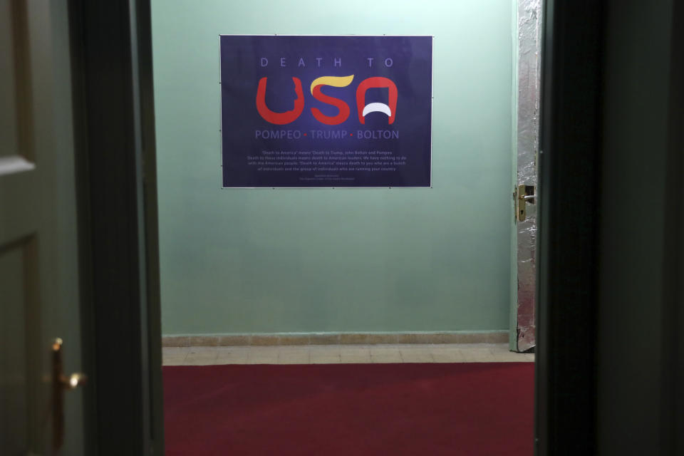 In this Sept. 26, 2019, photo, an anti-U.S. placard adorns a corridor of the former U.S. Embassy in Tehran, now partly a museum, Iran. The slogan in English reads: "Death to the USA," with the letter "U" bearing the profile of U.S. Secretary of State Mike Pompeo; the "S" the pompadour of President Donald Trump; and the "A" the mustache of former U.S. national security adviser John Bolton, a longtime hawk on Iran. (AP Photo/Vahid Salemi)