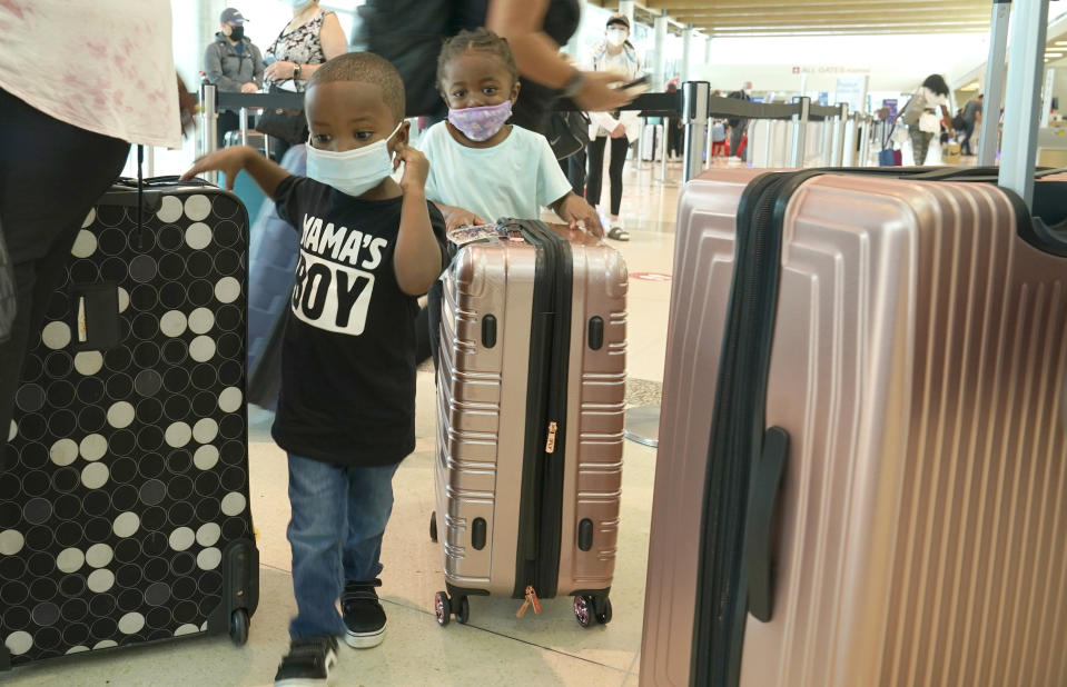 Traveling with their grandmother and mothers Karter Morrow, 2, stands with his cousin Gracie Jones, 3, as as they wait to check in for their flight to Long Beach from Love Field airport Friday, May 28, 2021, in Dallas. According to the kids grandmother, this is their first trip since the pandemic began over a year ago. (AP Photo/LM Otero)