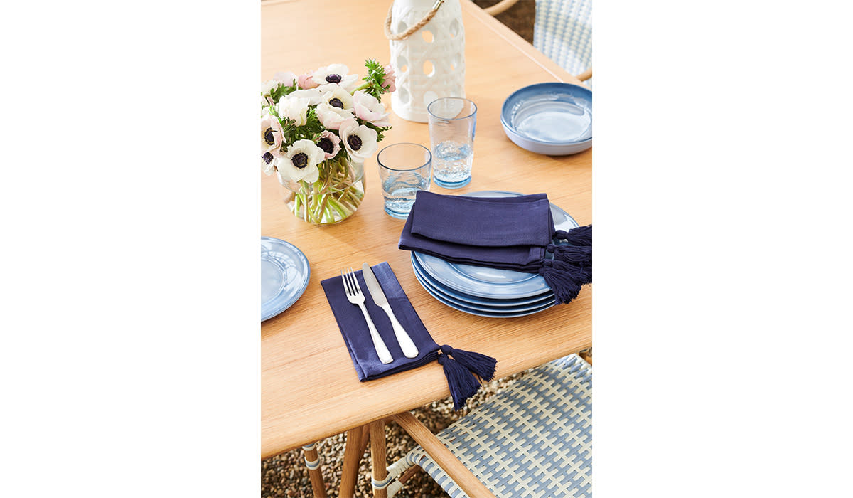 Table set with blue melamine plates, napkins, and silverware outdoors