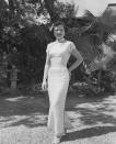 <p>A young woman wearing a brocade cheongsam with strappy sandals and a matching headpiece.</p>