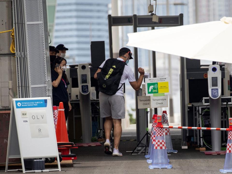 An Olympic athlete goes through a temperature check at the athlete's village