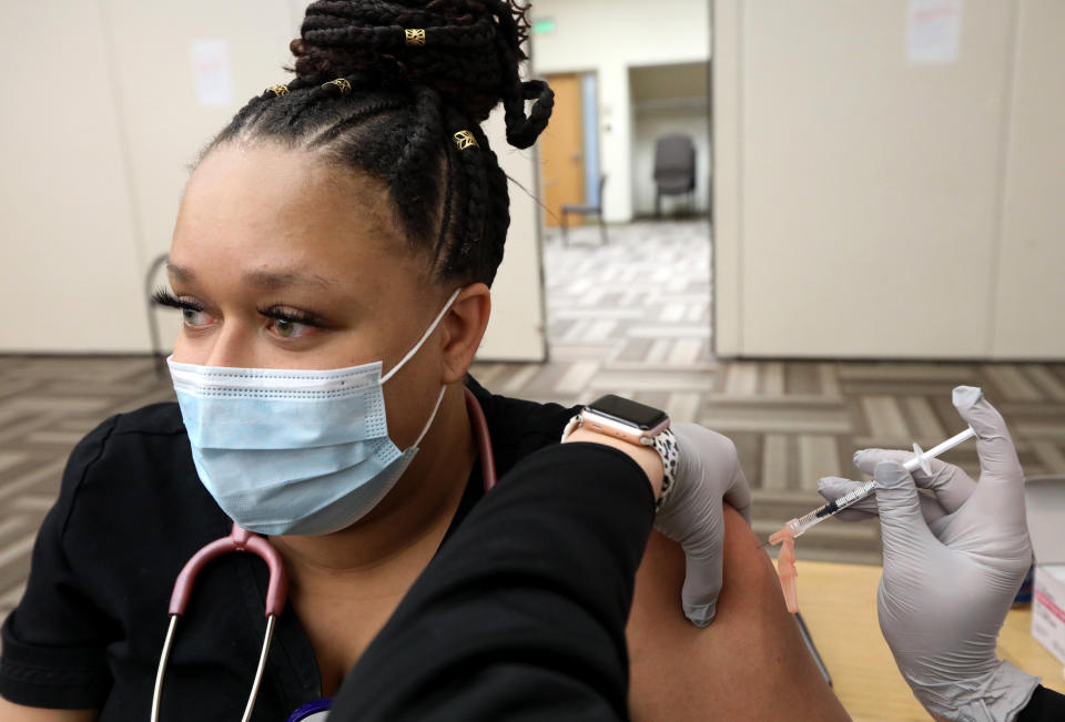 FILE - In this Dec. 14, 2020, file photo, respiratory therapist Leigha McDaniels receives a COVID-19 vaccination at Mercy Hospital St. Louis, in St. Louis. As the nation's COVID-19 vaccination campaign accelerates, governors, public health directors and committees advising them are holding key discussions behind closed doors, including debates about who should be eligible for the shots and how to best distribute them. (Laurie Skrivan/St. Louis Post-Dispatch via AP, File)